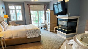 Una habitación de hotel con una cama grande, televisión, chimenea y bañera.