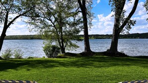 Vista de un lago con dos sillas a rayas y una mesa al frente.