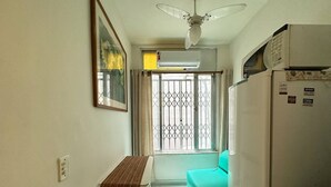 A small, compact kitchen with a dining area, a ceiling fan, an air conditioner, and a refrigerator. - Studio Sá Ferreira (Copacabana Rio de Janeiro)