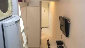 A compact kitchen with white cabinets, a microwave, and a small dining table with chairs. - Studio Sá Ferreira (Copacabana Rio de Janeiro)