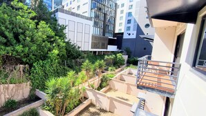A modern building with a balcony, surrounded by lush greenery and other residential structures. - Urban CBD Perth A GEM 1Bedroom Apartment (Perth)