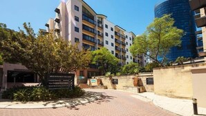 A modern building with balconies, a sign for 'Mounts Bay Village', and a nearby blue glass building. - Urban CBD Perth A GEM 1Bedroom Apartment (Perth)