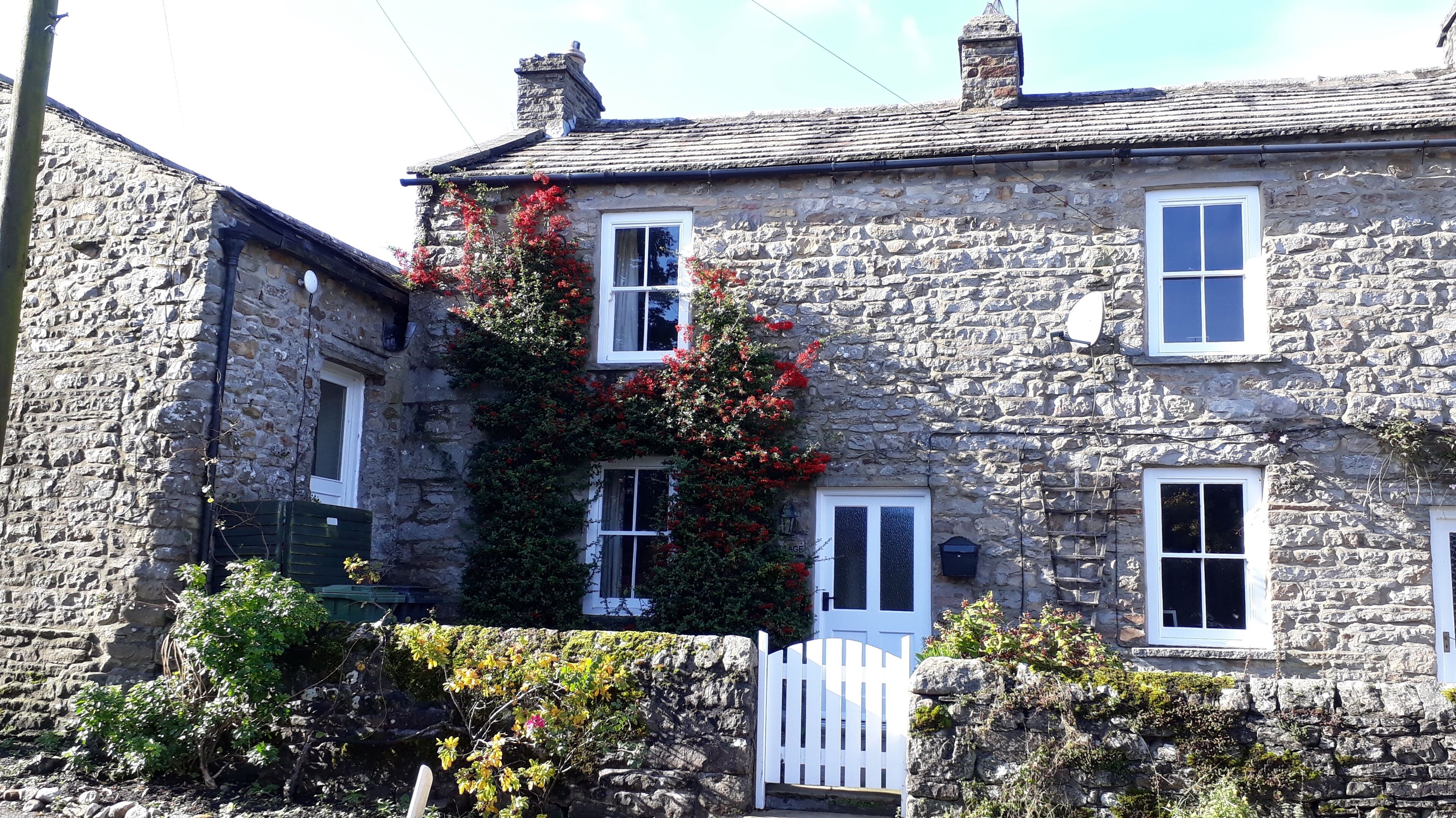 A stone building with multiple windows and a white gate.
