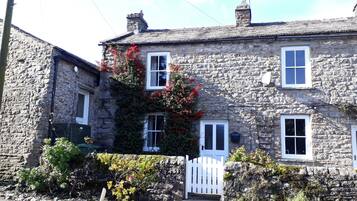 A stone building with multiple windows and a white gate.