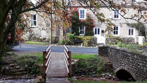 A stone bridge leading to a stone building with multiple windows and a stone wall. - A dales bolthole & quintessential country cottage – cosy, appealing & in an idyllic rural setting (Richmond)