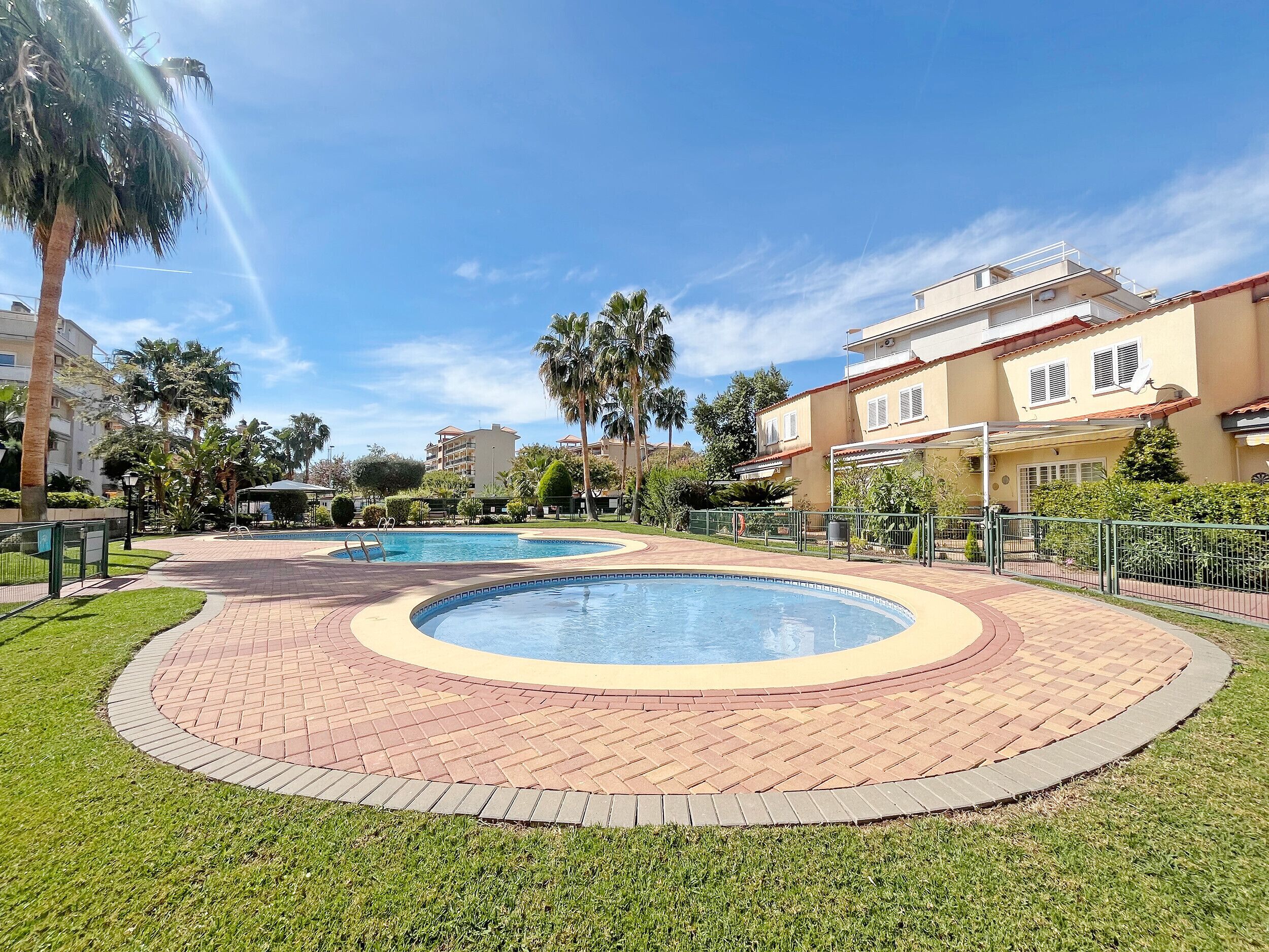 A resort with a circular pool area, palm trees, and a building with balconies.