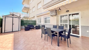 An outdoor patio area with a dining table and chairs, a covered seating area, and a small shed. - Global Vacacional: Practical flat in Canet Beach (Canet d´en berenguer)
