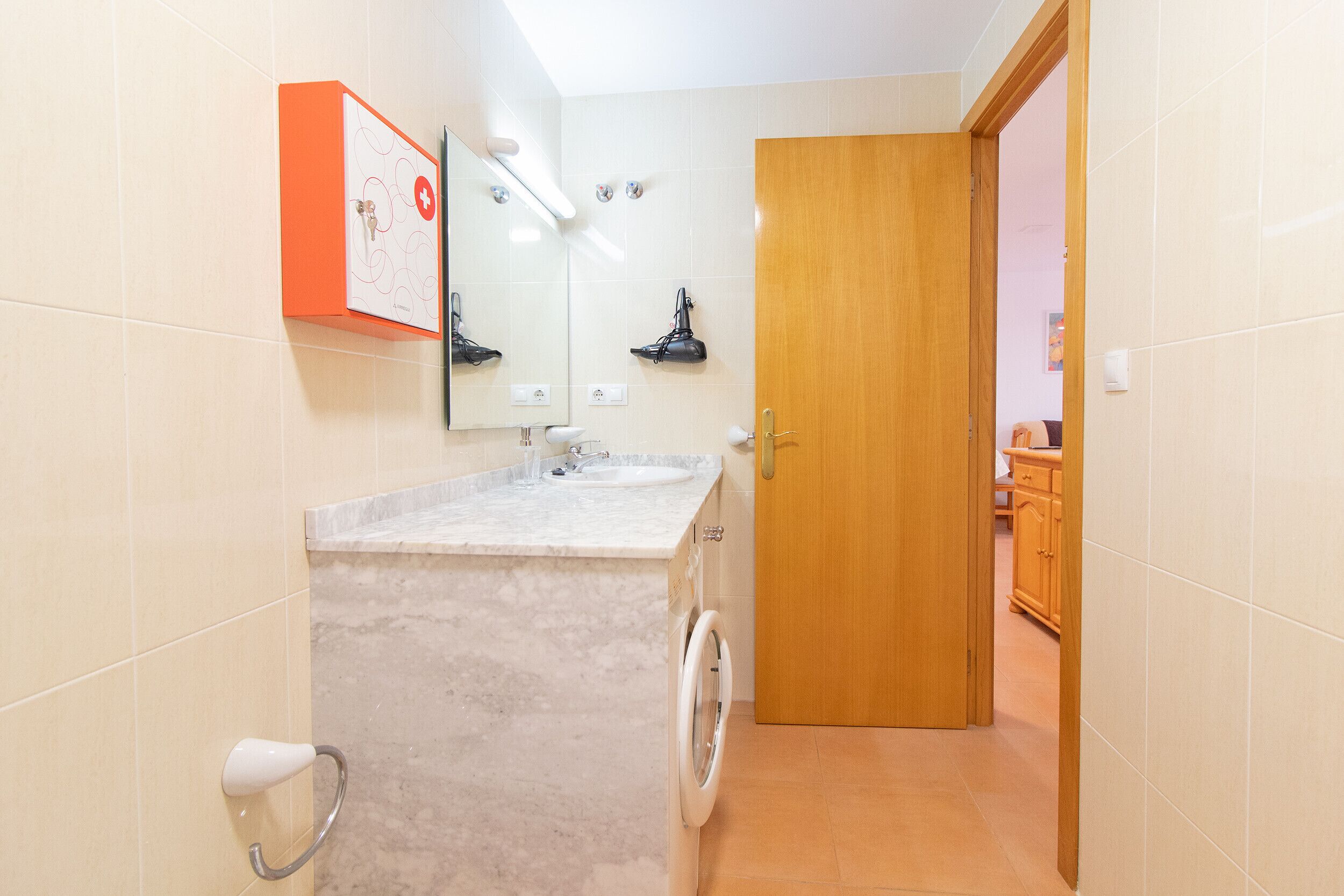 A bathroom with a sink, mirror, and a wooden door leading to another room.
