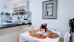 Ein weißer Esstisch mit bunten Untersetzern, einer Schüssel mit Snacks und einem Spiegel an der Wand.