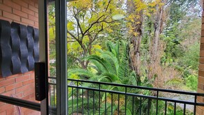 Ein Balkon mit Blick auf einen üppigen Garten und Bäume.
