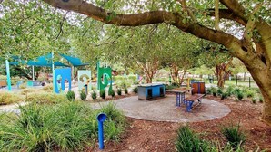 A park with a playground, seating areas, and a large tree. - Serenity & Comfort in Subiaco 1 Bedroom Unit (Subiaco)