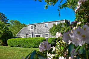 A two-story house with a well-maintained lawn and a hedge in the foreground. - Walk to Skaket Beach, Great Backyard! (Orleans)