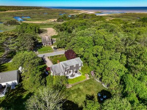 A large house with a spacious lawn, a driveway, and a view of a coastal landscape. - Walk to Skaket Beach, Great Backyard! (Orleans)