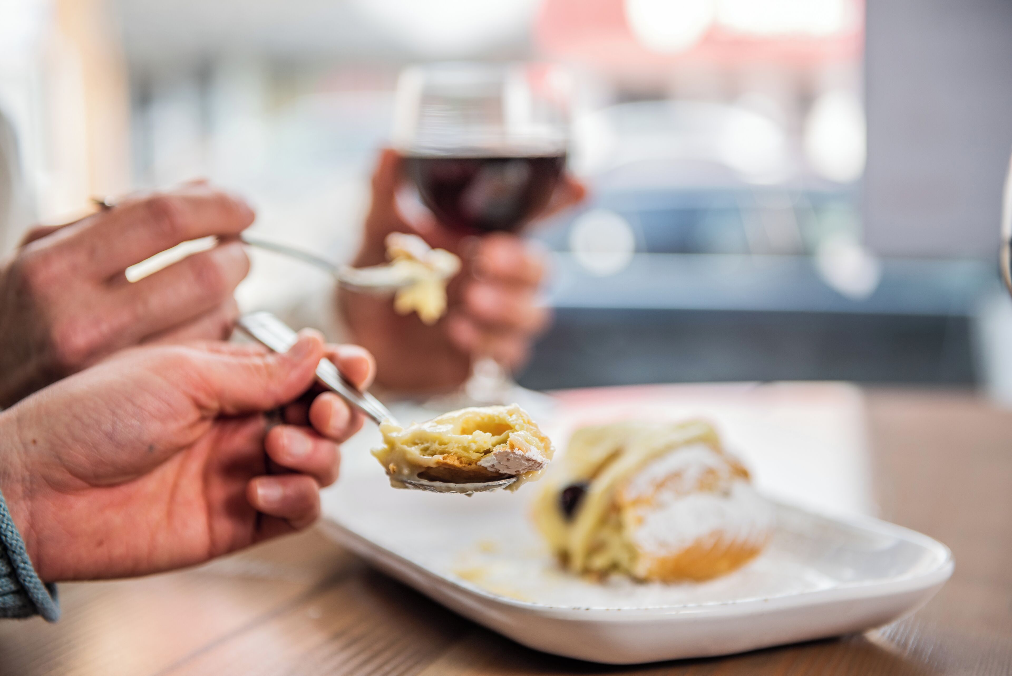 A dining table with a plate of food and a glass of red wine.