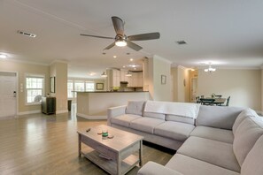 Un salon spacieux avec un canapé d’angle, une table basse et un ventilateur de plafond.