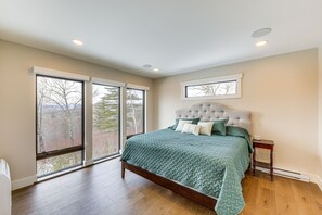 Ein Schlafzimmer mit einem großen Bett, einem Fenster und Blick auf Bäume.