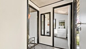 Un intérieur moderne avec un escalier, une commode blanche et un miroir qui reflète une salle de bain.