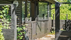 Une cabane en rondins avec une véranda, une fenêtre et une porte.