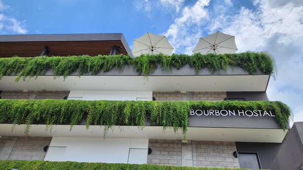 A building with a sign reading "BOURBON HOSTAL" and two umbrellas on the roof.