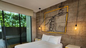 Een moderne slaapkamer met een groot bed, houten vloeren, een glazen deur naar een balkon en een uniek kunstwerk aan de muur.