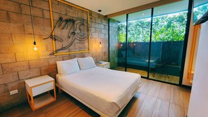 Een moderne slaapkamer met een groot bed, een bakstenen muur en een glazen deur die leidt naar een buitenruimte.