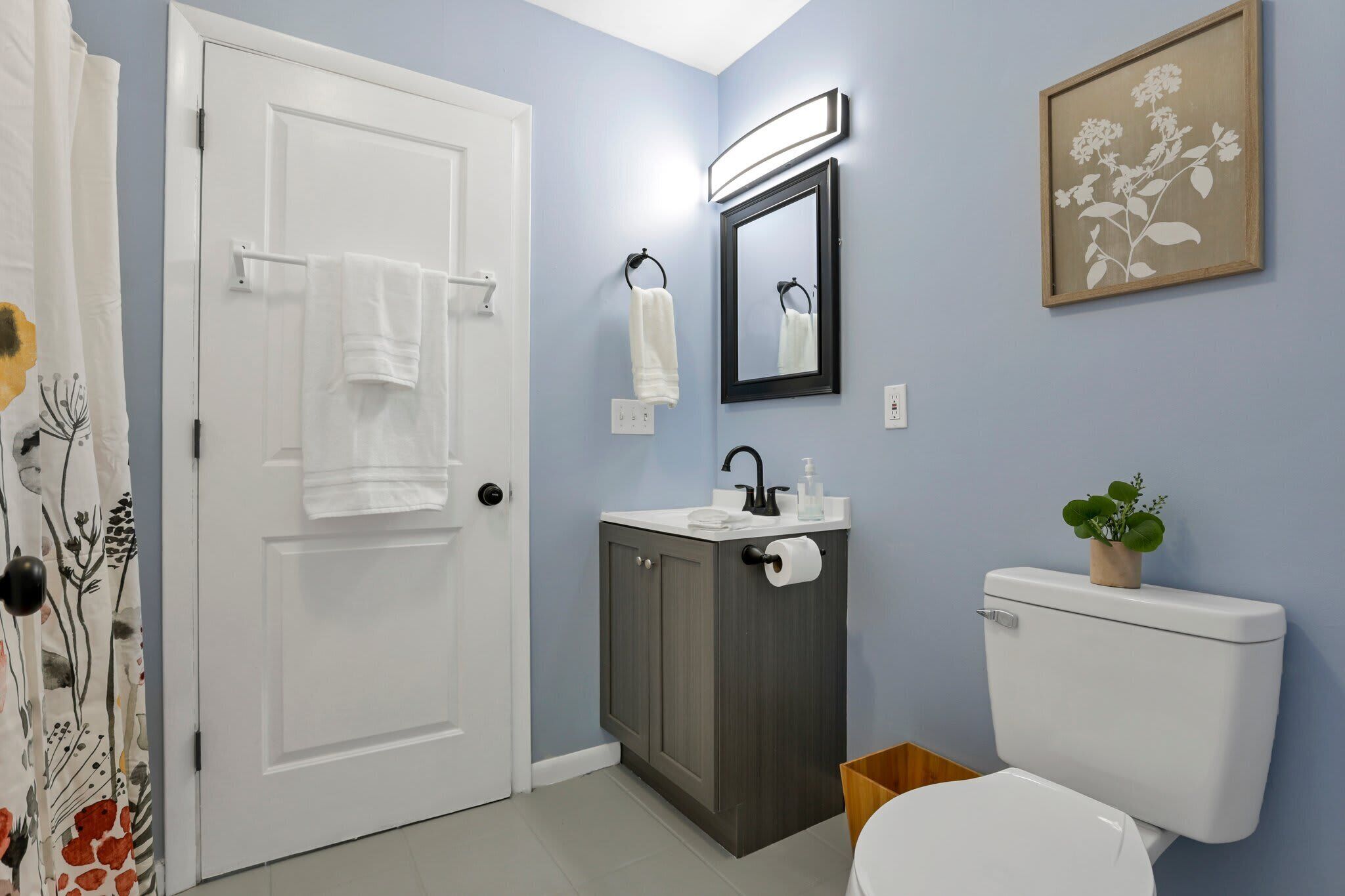 A bathroom with a white toilet, a sink with a mirror above it, and a towel rack with two towels.