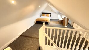 A bedroom with a bed, a desk, and a chair in a sloped ceiling room. - Nice and Cosy one bed flat
 (Carshalton)