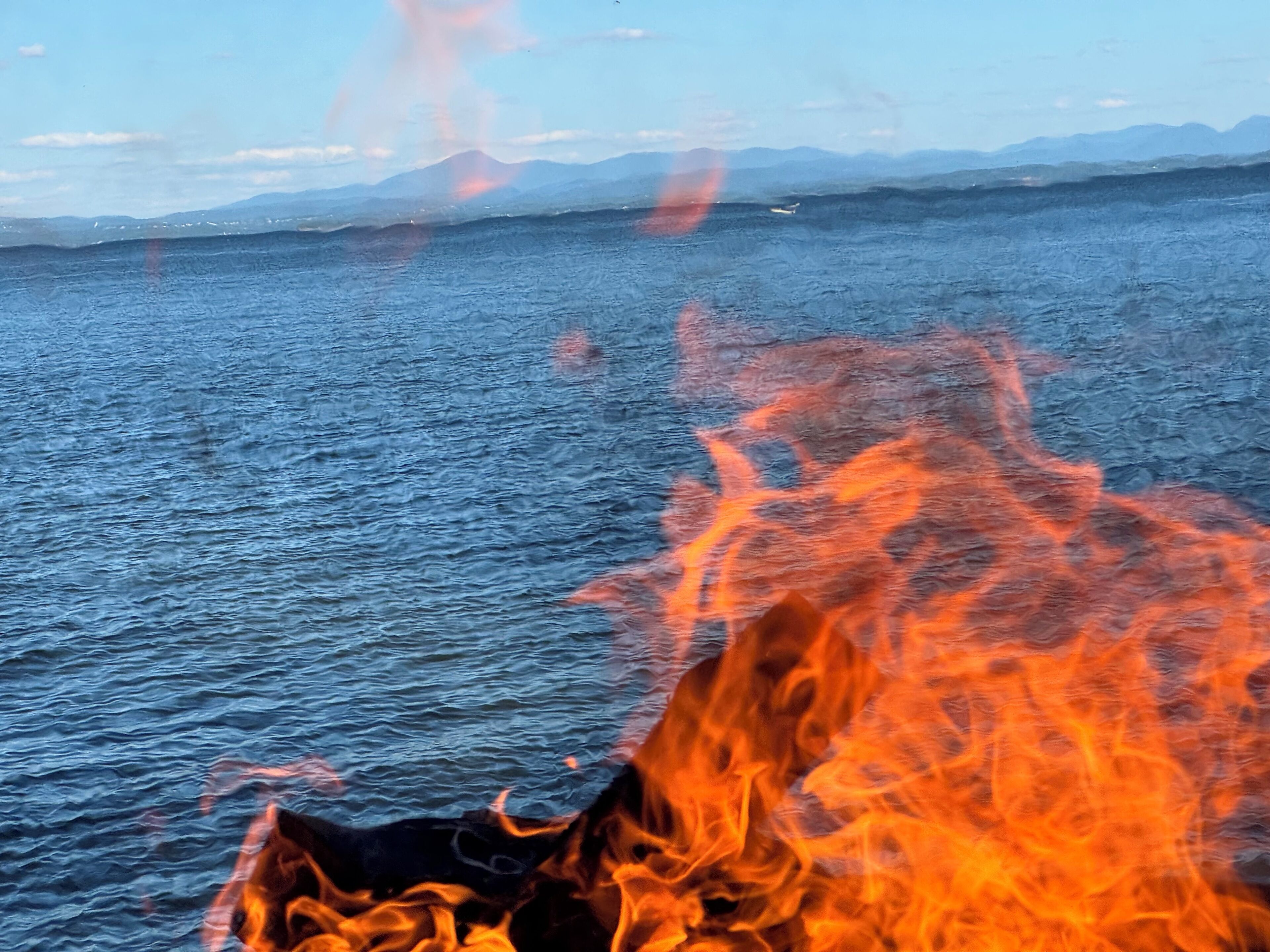 En vattenyta med en eld som brinner vid stranden.