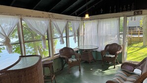 A covered porch with wicker furniture, a glass table, and sheer curtains. - A New York camp on Lake Champlain, private pebble beach frontage. (Keeseville)