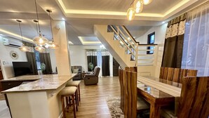Una cocina moderna con una isla central, mesa de comedor de madera y una escalera que conduce a un nivel superior.