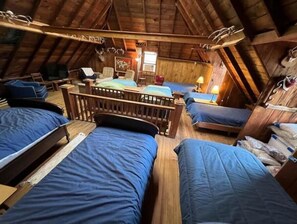 Cozy attic bedroom with a central bed frame, two single beds, and a small table with a chair.