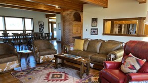 A spacious living room with a wooden floor, leather sofas, a coffee table, and a patterned rug.