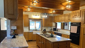 A modern kitchen with wooden cabinets, a large island, and pendant lighting.
