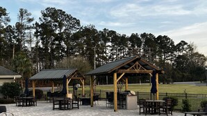 A pool area with a wooden gazebo, outdoor seating, and a view of a golf course. - Lake Side Condo Getaway (Santee)