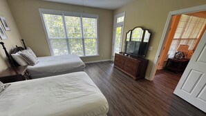 A bedroom with two beds, a dresser, a TV, and a window with blinds. - Lake Side Condo Getaway (Santee)
