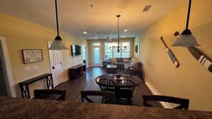 A spacious kitchen with granite countertops, a dining area with a round table and chairs, and a living room with a sofa and a TV. - Lake Side Condo Getaway (Santee)