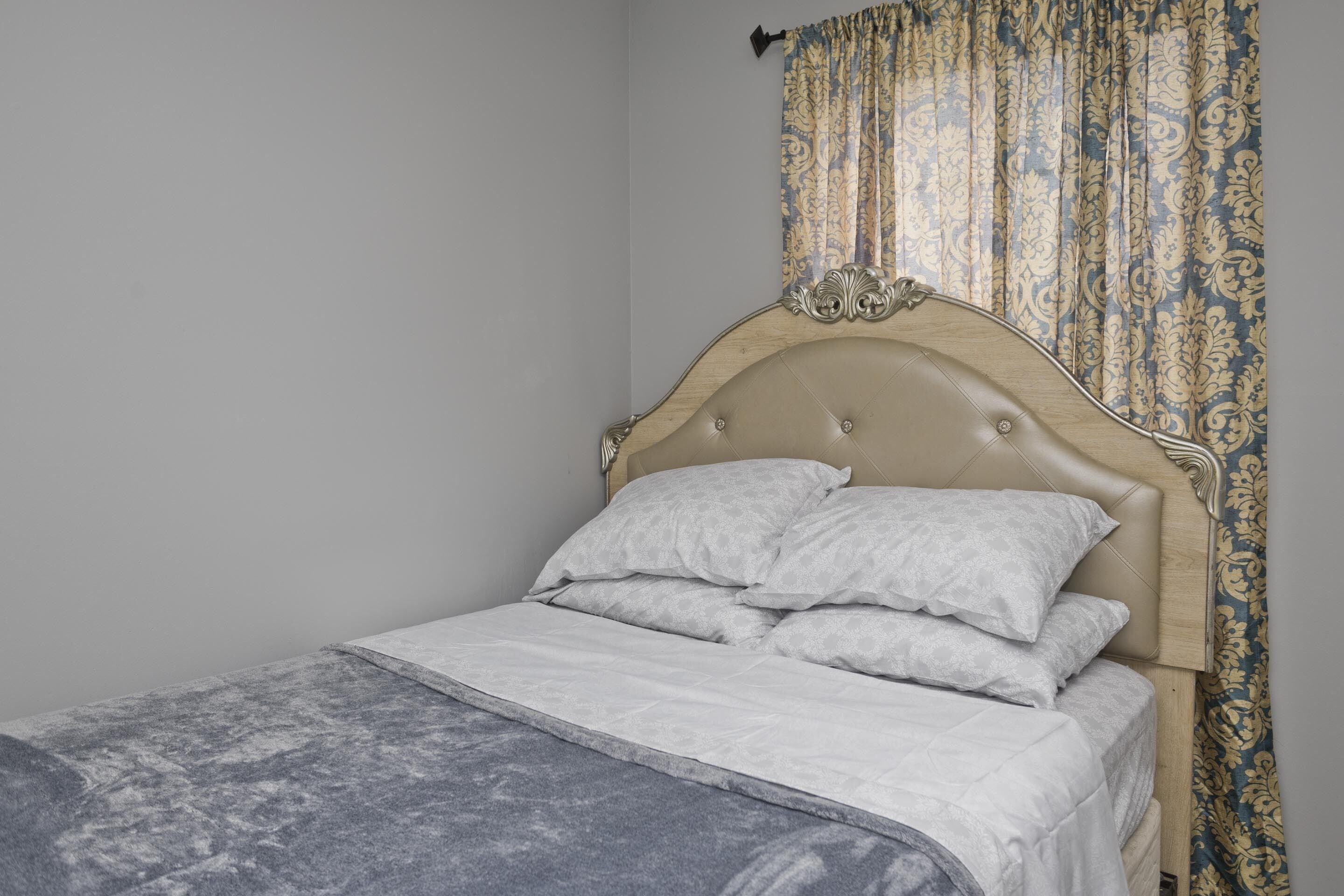 A bed with a headboard, a bedspread, and pillows.