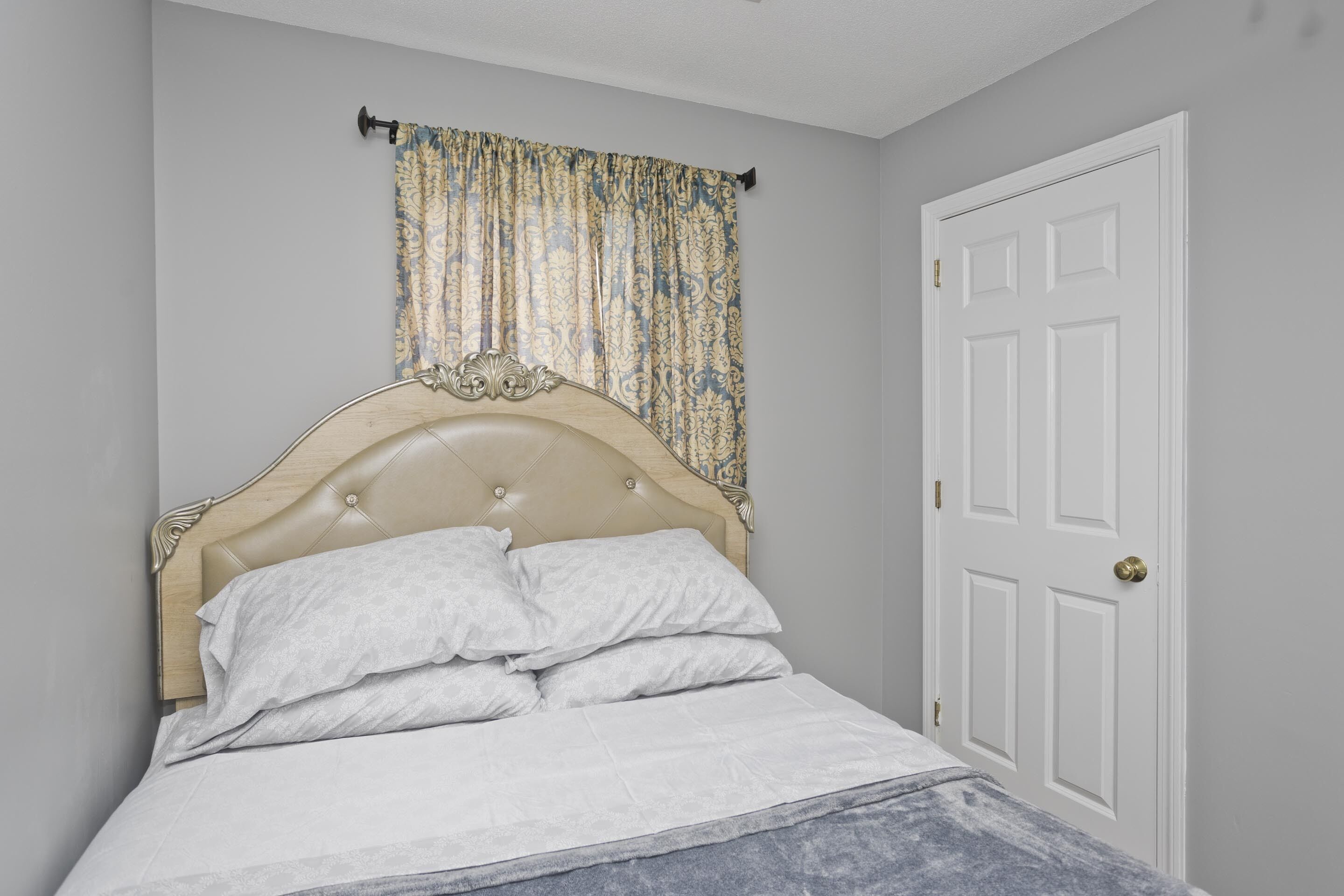 Une chambre à coucher avec un lit, une porte et un rideau.