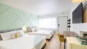 Une chambre d’hôtel avec deux lits, une table à manger, un téléviseur et une kitchenette.