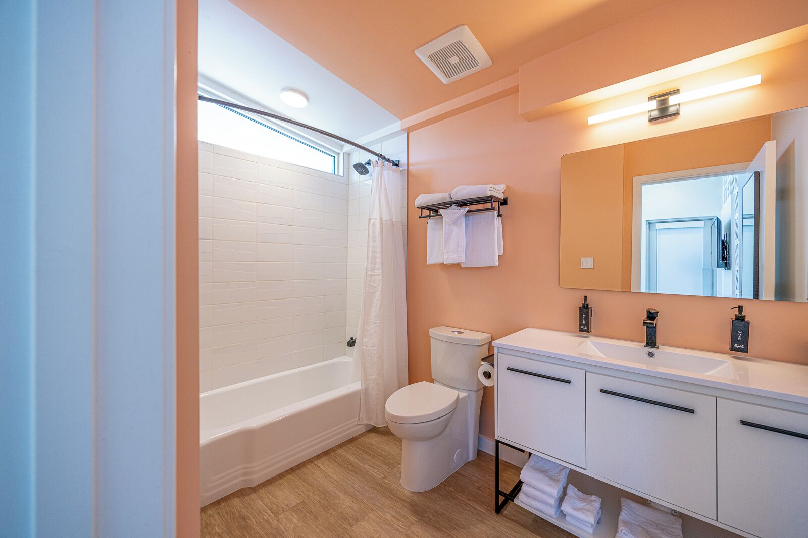 A bathroom with a bathtub, toilet, and a vanity with a mirror and sink.