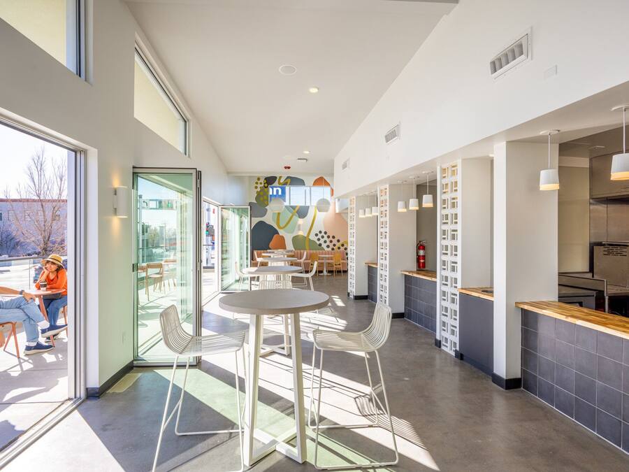 Un interno moderno con un'area bar, posti a sedere e vista attraverso delle porte vetrate.
