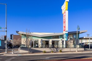 Un motel con un letrero grande, asientos al aire libre y un diseño moderno.