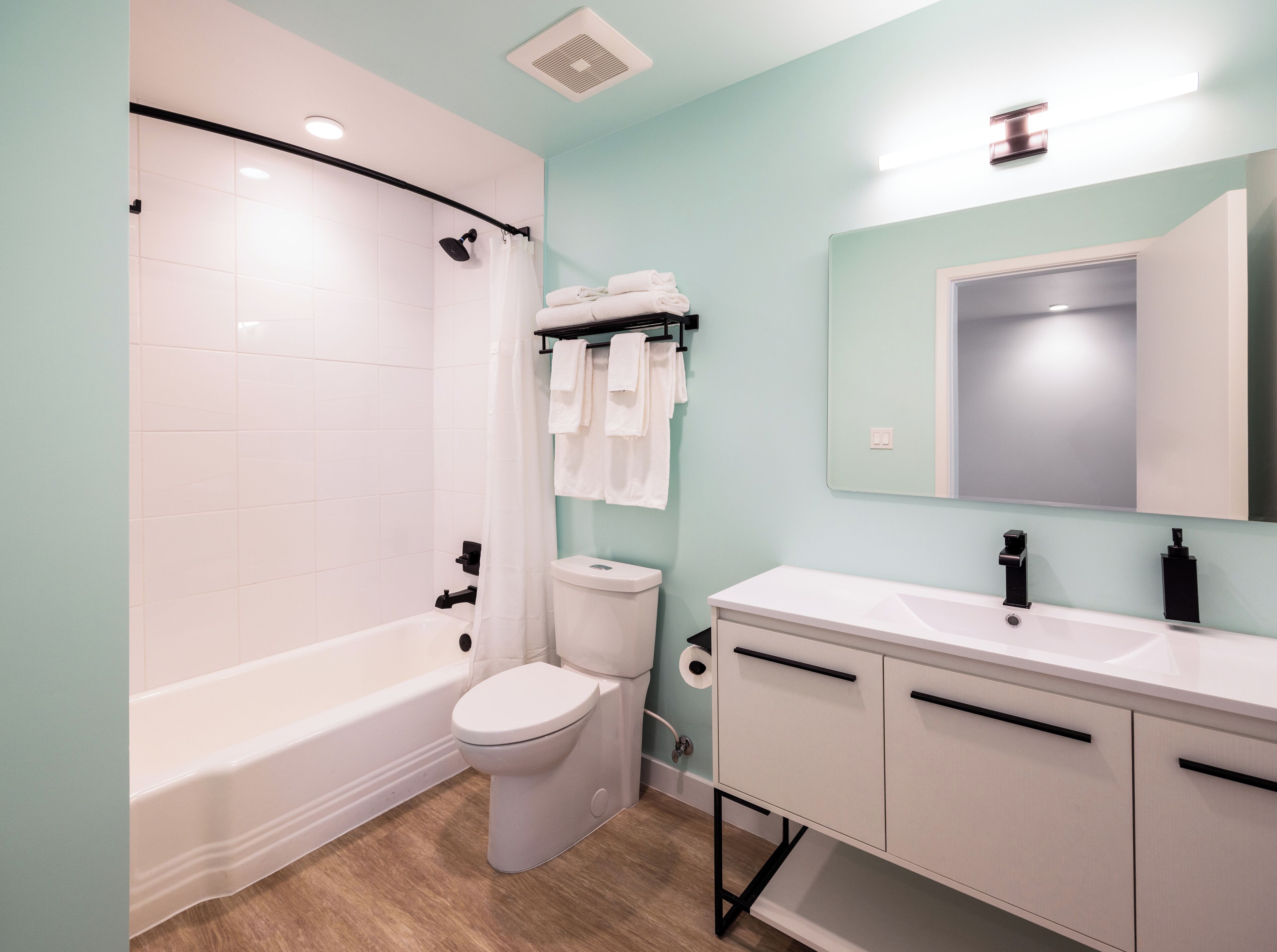 Een moderne badkamer met een bad, toilet en wastafel met spiegel.