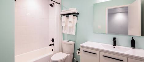 Een moderne badkamer met een bad, toilet en wastafel met spiegel.