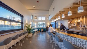 Un bar moderno con asientos, una barra y vistas a la ciudad a través de amplios ventanales.