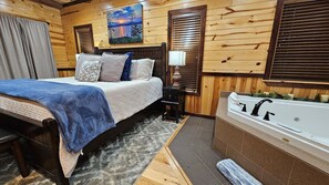 Une chambre à coucher aux murs lambrissés, comprenant un lit, une table de chevet, une lampe et une salle de bain avec une baignoire.