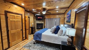 Une chambre confortable dans un chalet en bois, avec un lit, une télévision et une cheminée.