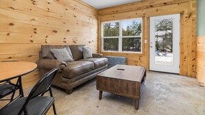 Ein gemütliches Zimmer mit einer braunen Ledersofa, einem Holztisch und einem Esstisch mit Stühlen.