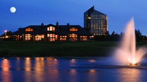Ein großes Hotel mit mehreren Gebäuden, einem Teich mit einer Fontäne und einem Mond am Himmel.