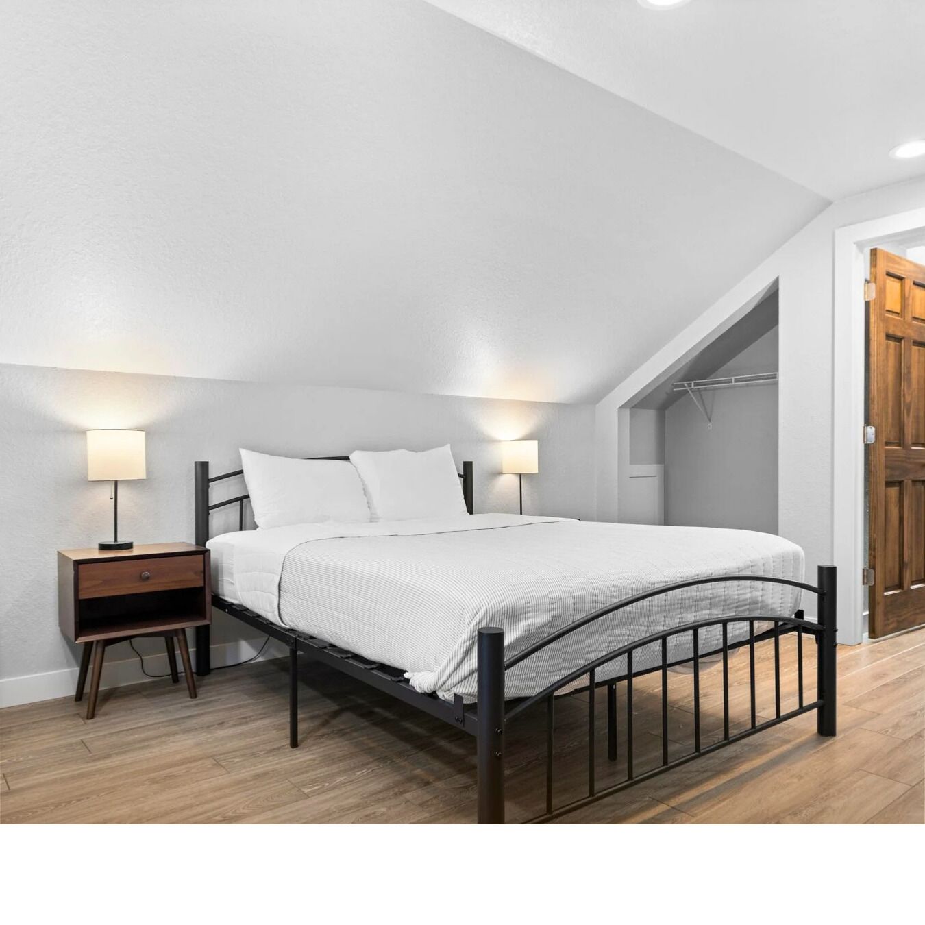 Une chambre à coucher avec un lit, des tables de chevet et des lampes fixées au mur.